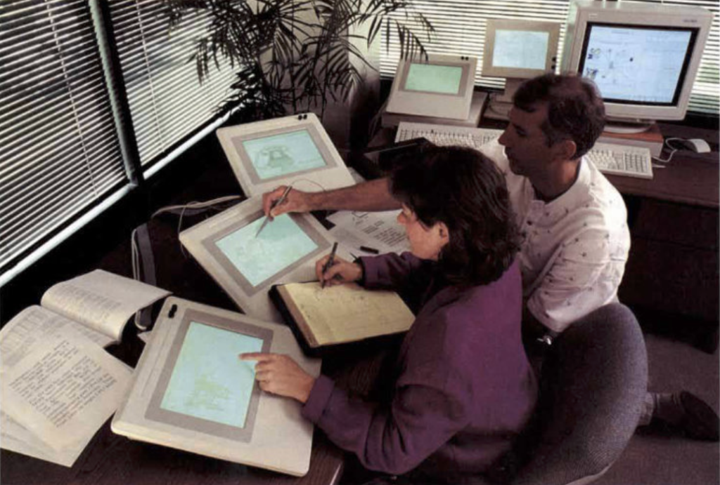 Researchers working and using pen and pad alongside large tablet devices circa 1990
